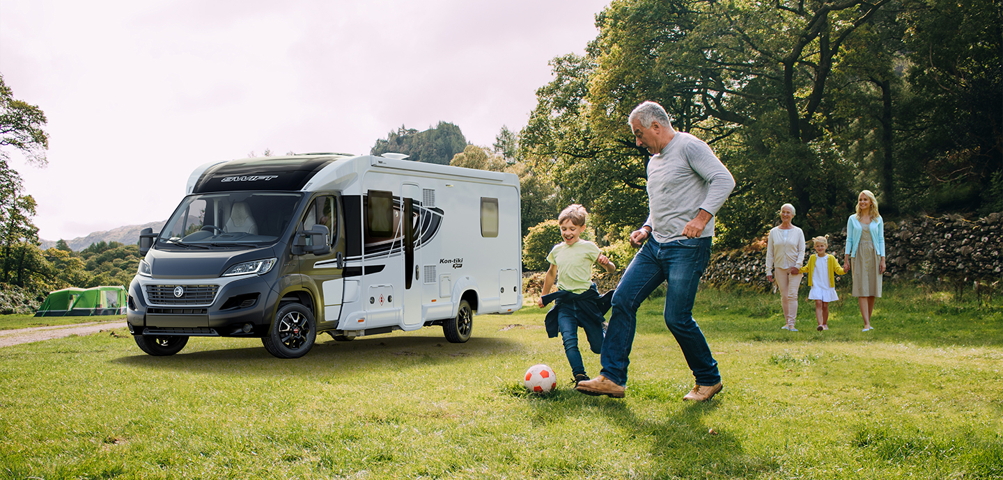 Father and son playing football in front of Motorhome